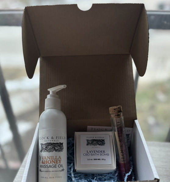 Angled shot of the Evening Bliss Self-Care Collection box with CBD massage oil prominently displayed, showcasing its soothing blend of honey and vanilla for ultimate relaxation.